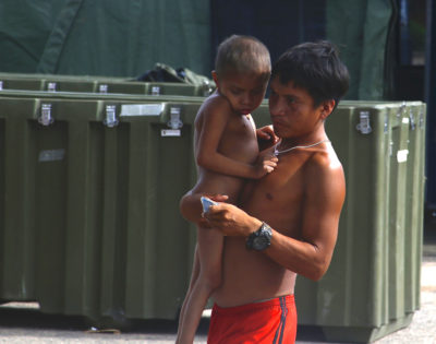 A Yanomami man carries a child outside an Army field hospital in Roraima, Brazil last week.