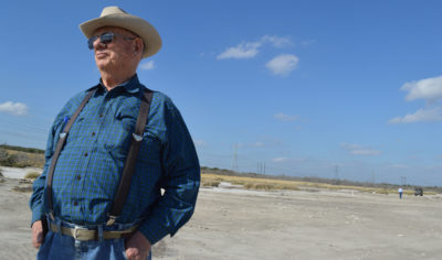 Alonzo Peeler Jr. stands in an area where the vegetation has died off, directly next to a coal ash pond.